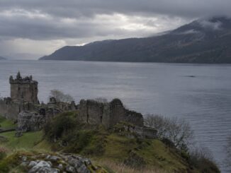 Urquhart Castle dominant le Loch Ness avec une longue forme sombre visible à la surface de l’eau