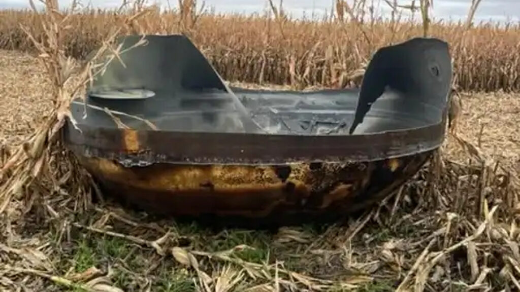 Photographie réelle, vue de face, du grand fragment métallique retrouvé dans le champ de maïs de Scott Township au Minnesota en octobre 2026